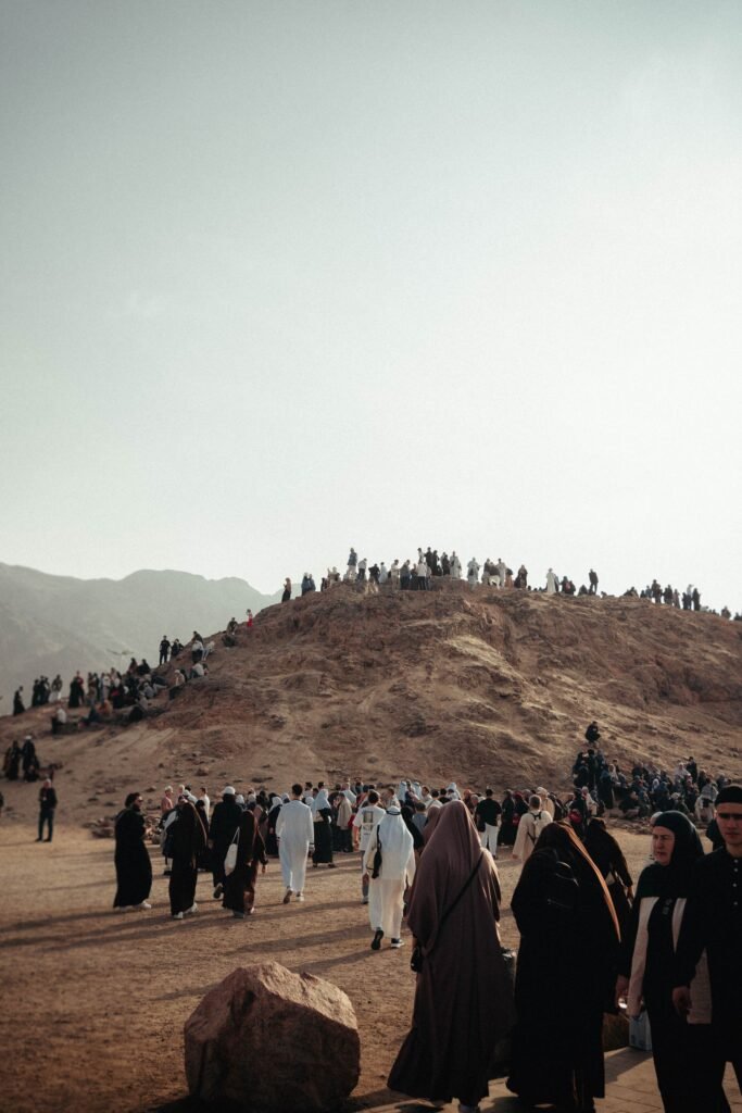 Group of pilgrims in traditional attire gathered on a sandy hill