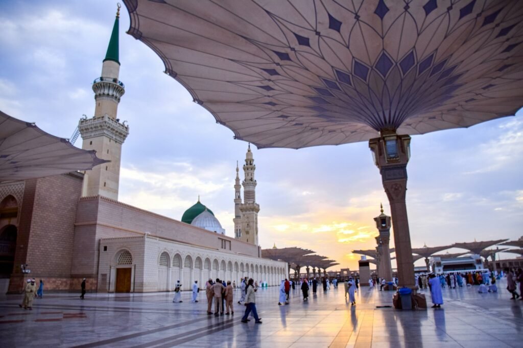 Pilgrims walking in the courtyard of the Prophet's Mosque under large umbrellas, Madinah